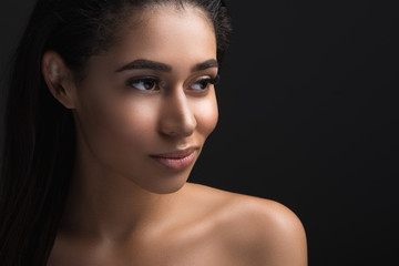 Fototapeta premium Portrait of thoughtful female person having perfect facial and body skin. Copy space in right side. Isolated on black background