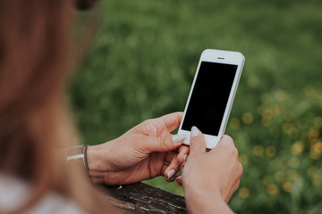 Empty copy space black screen of white mobile phone in young girl hands outdoor.