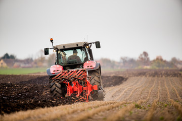Fototapeta premium Farmer plowing stubble field