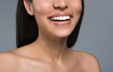 Close up of female lower face and bare body. She is showing snow white perfect teeth. Isolated on background