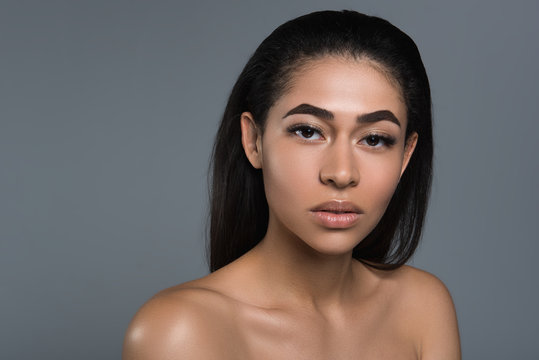 Portrait of attractive girl staring at camera with tranquility. Her derma looking great and healthy. Copy space in left side. Isolated on background