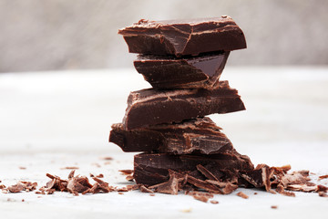 dark chocolate bars on stone table and broken pieces of cocoa