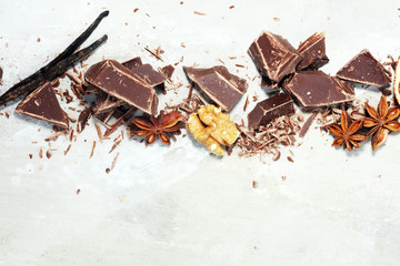 dark chocolate bars  with anise and nutson stone table and broken pieces of cocoa