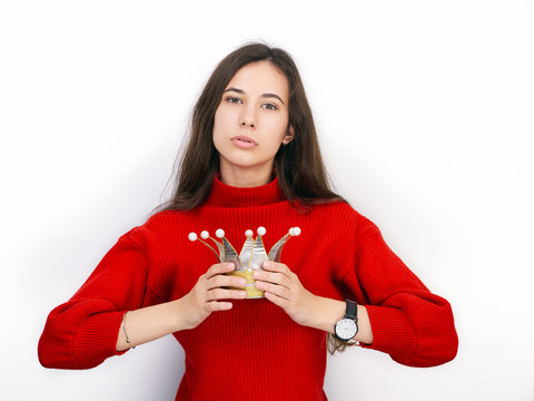 Young beautiful brunette woman in red sweater and diy crown playing princess against white background