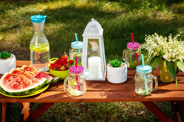 picnic table with juicy fruits and delicious lemonade in a summer park