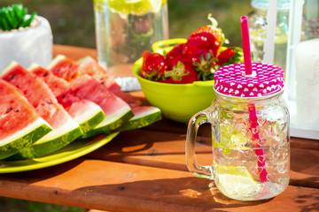 glass with a straw full of delicious lemonade on a picnic table in the park