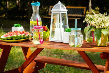 picnic table with juicy fruits and delicious lemonade in a summer park
