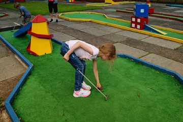 Children playing mini golf in park.