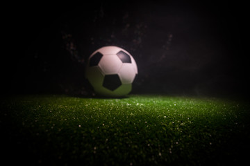 Traditional soccer ball on soccer field. Close up view of soccer ball (football) on green grass with dark toned foggy background. © zef art