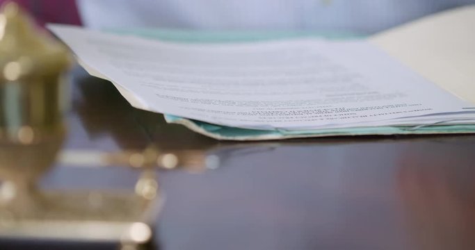 close up businessman opening folder and writing on legal documents