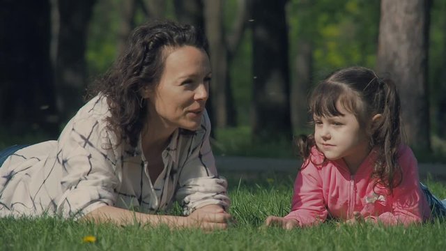 Family in the park. A daughter with mother on the green grass.