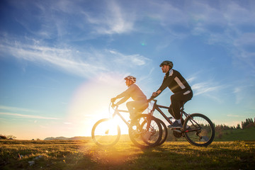 Fototapeta na wymiar Happy mountainbike couple outdoors have fun together on a summer afternoon sunset