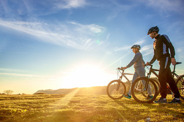 Naklejka na ściany i meble Happy mountainbike couple outdoors have fun together on a summer afternoon sunset