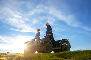 Beautiful couple is watching the sunset from the mountain sitting on atv quadbike © FS-Stock