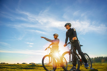 Fototapeta premium Biker couple with mountain bike pointing in distance at countryside
