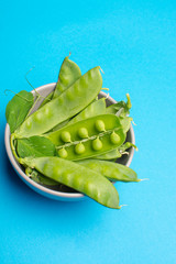 Fresh green ripe green peas in bowl copy space close up isolated on trendy blue background