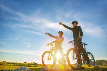 Biker couple with mountain bike pointing in distance at countryside © FS-Stock