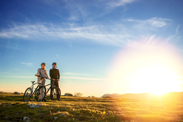 Happy mountainbike couple outdoors have fun together on a summer afternoon sunset