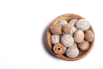 Stone bowl with nutmeg, muscat nuts, copy space close up isolated on white background