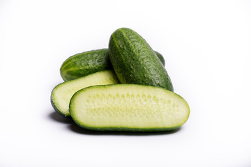 Fresh small green cucumbers whole and sliced close up copy space isolated on white background