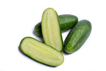 Fresh small green cucumbers whole and sliced close up copy space isolated on white background