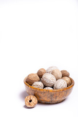 Stone bowl with nutmeg, muscat nuts, copy space close up isolated on white background