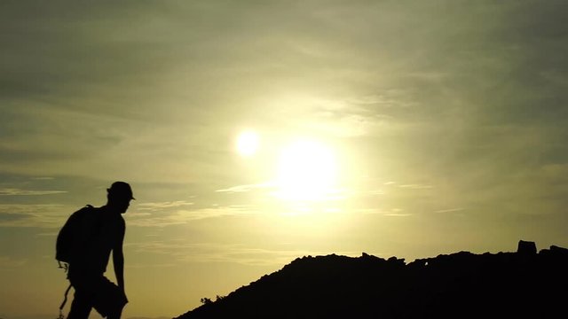 Silhouette of travel hiking man on the rock in slow motion