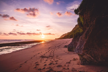 Tropical sandy beach with rocks and sunset or sunrise colors