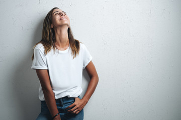 Happy woman in white blank t-shirt, grunge wall, horizontal studio portrait - Powered by Adobe
