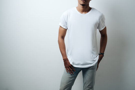 Man wearing white blank t-shirt, empty wall, horizontal studio close-up