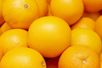 Vibrant ripe oranges in peel. Tropical fruit on market. Sunny yellow citrus fruit for juice or cooking.