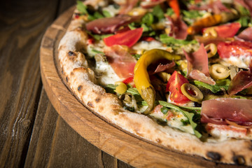 close up view of freshly baked italian pizza on wooden cutting board