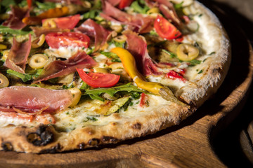 close up view of freshly baked italian pizza on wooden cutting board
