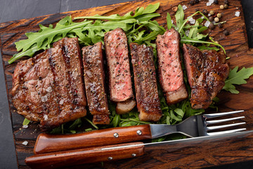 Closeup ready to eat steak new York beef breeds of black Angus with herbs, garlic and butter on a...