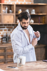 Fototapeta na wymiar handsome loner businessman with unbuttoned shirt looking down at kitchen