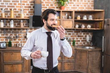 handsome loner businessman eating toasts on breakfast at kitchen