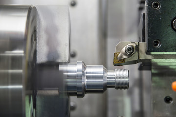 The CNC lathe machine or turning machine cutting the thread at the aluminium shaft part.Modern manufacturing process.