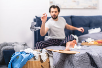 loner throwing dirty sock into basket with laundry in bedroom