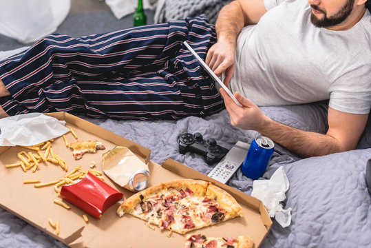 cropped image of loner using tablet on bed in bedroom