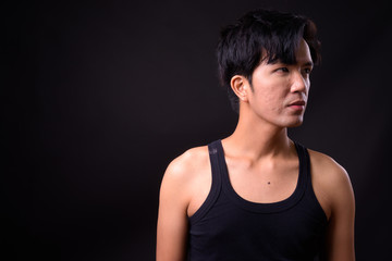 Fototapeta na wymiar Young handsome Asian man against black background