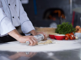 chef preparing dough for pizza with rolling pin
