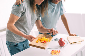 cropped image of woman embracing boyfriend while he cooking at kitchen