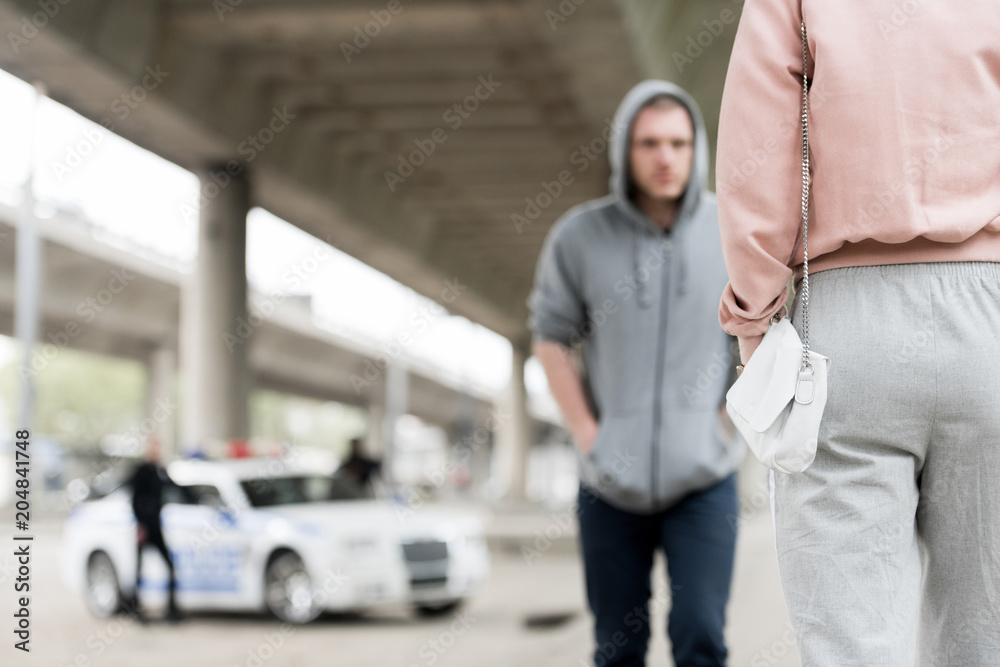 Wall mural cropped shot of woman with handbag and thief in hoodie