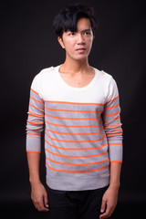 Young handsome Asian man against black background