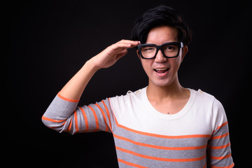 Young handsome Asian man against black background