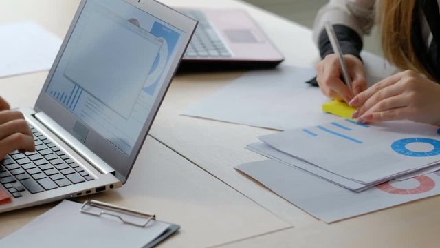 business data analysis paperwork. office workers casual workday routine. man and woman at their workplaces typing on laptop and writing a memo