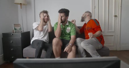 Cheerful Mexican football supporters celebrating goal while watching football match on television at home