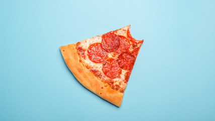 bitten pizza pepperoni slice isiolated on blue background