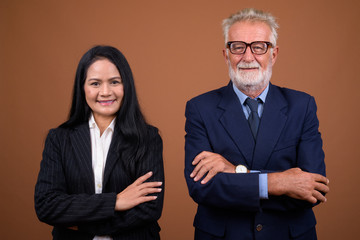 Mature multi-ethnic business couple against brown background