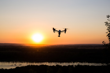 silhouette of drone, quadrocopter with photo camera flying in the sky.
